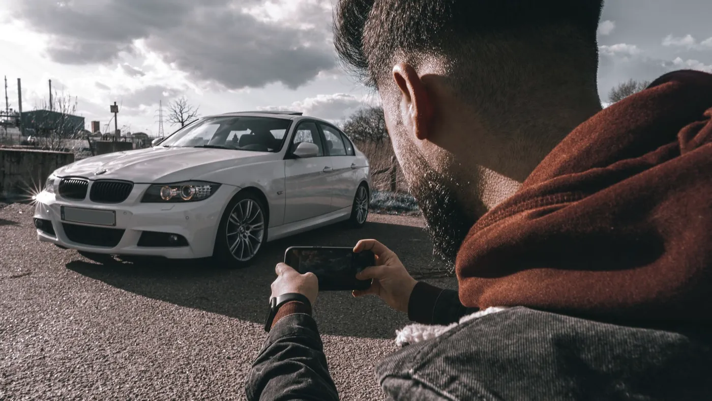 Mand fotograferer sin bil med mobilen